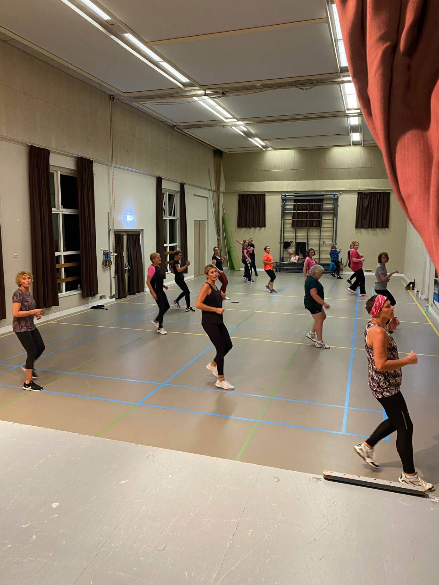 Groep in beweging tijdens een Zumbales in de gymzaal