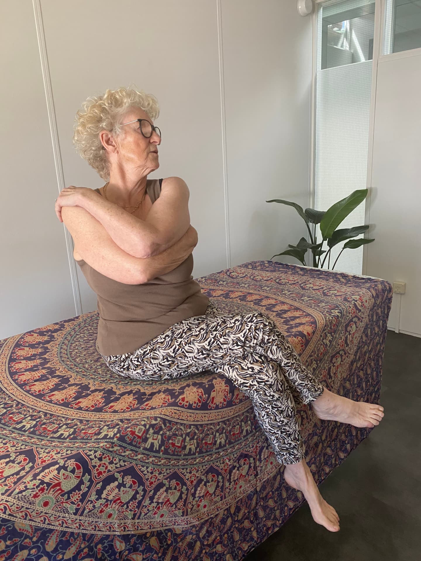 Cliënt voert een Fascial Maneuvers-oefening uit op de behandeltafel in de praktijkruimte