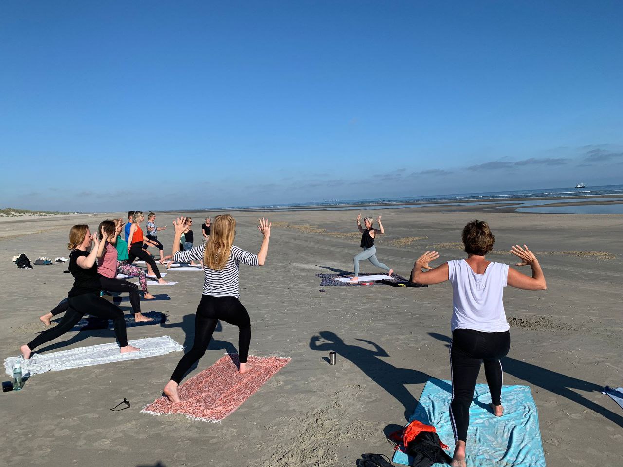 Groep doet yoga op het strand van Ameland